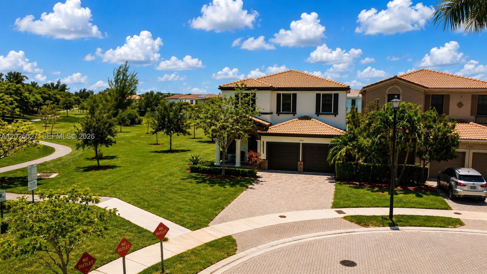 A two-story house with a tile roof and a paved driveway sits beside a park — 19220 NE 9th Pl, Miami FL 33179, MIAMI, FL