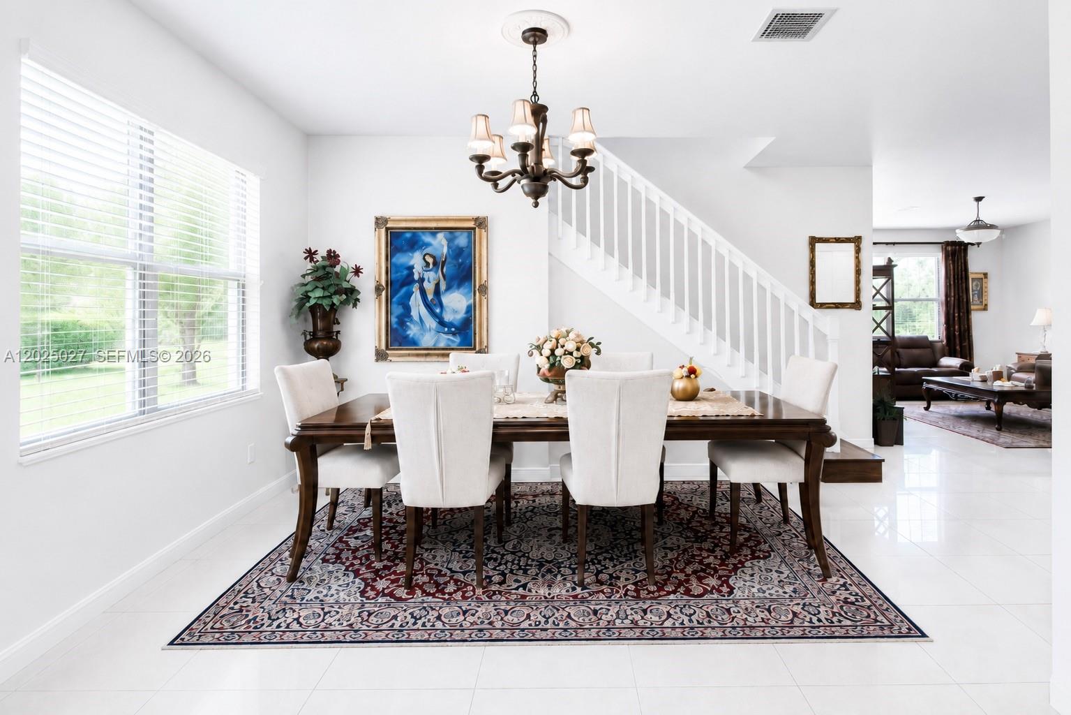 A dining room features a wooden table, upholstered chairs, a chandelier, and a staircase — 19220 NE 9th Pl, Miami FL 33179, MIAMI, FL