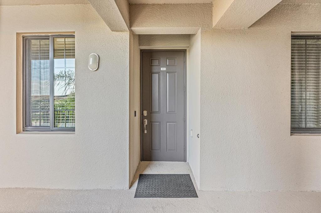 A gray front door with a small number plate is centered between two windows — 17810 GAWTHROP DRIVE UNIT 304, BRADENTON, FL
