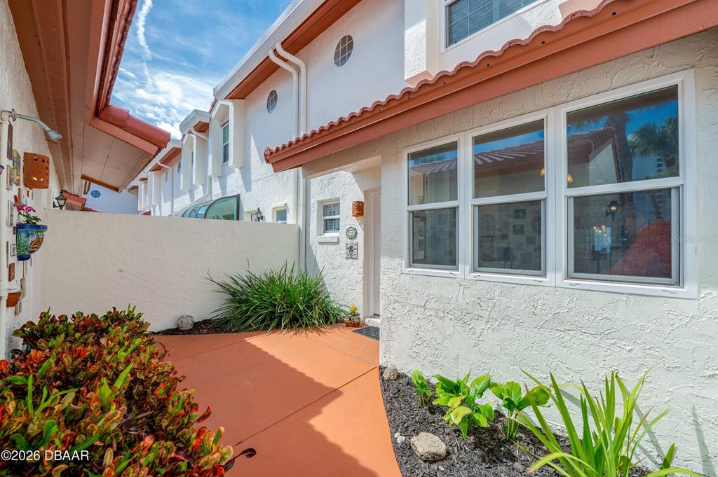 A white stucco townhouse exterior features a terracotta patio, landscaping, and large windows — 226 FLORIDA SHORES BOULEVARD, DAYTONA BEACH, FL