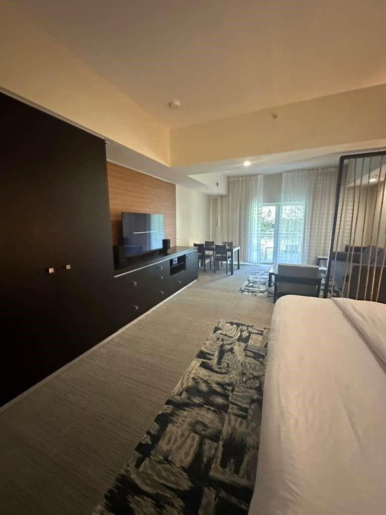 A hotel room featuring a bed, a dark media console, and a dining area near windows — 5300 NW 87th Avenue # 706, Miami FL 33178, MIAMI, FL