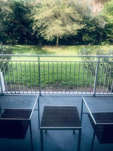 A balcony with two chairs and a small table overlooks a grassy yard and trees — 5300 NW 87th Avenue # 706, Miami FL 33178, MIAMI, FL