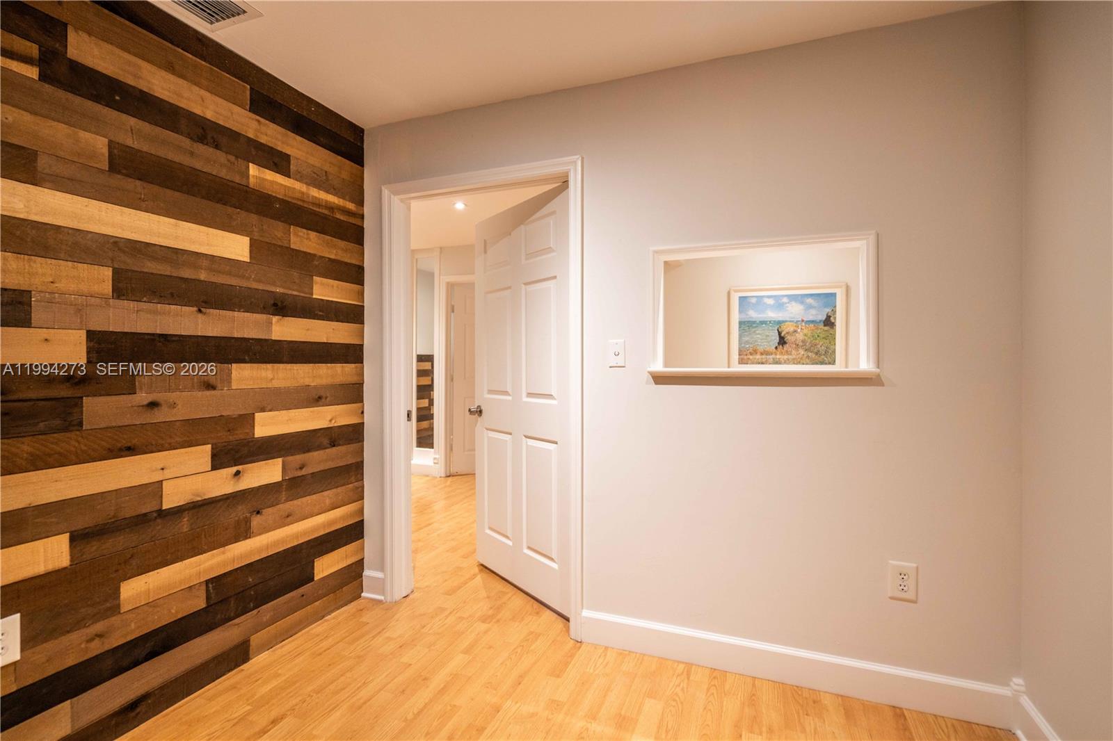 A room features a wood-paneled accent wall, light hardwood floors, and a recessed wall mirror — 3119 Coral Way # 200, Miami FL 33145, MIAMI, FL
