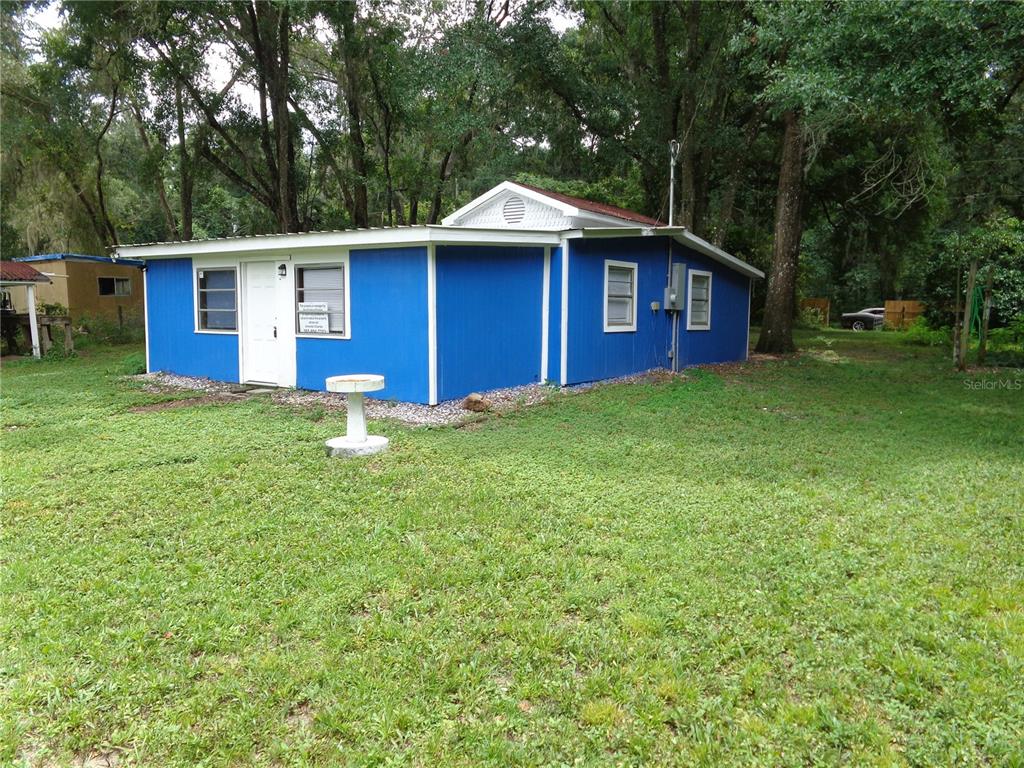 A blue, single-story house with a white door and metal roof sits on a grassy lot — 2878 NE 161ST STREET, CITRA, FL
