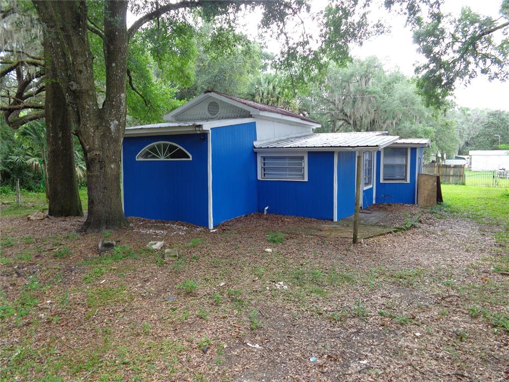 The exterior of a blue, single-story house features a metal roof and a small wooden deck — 2878 NE 161ST STREET, CITRA, FL