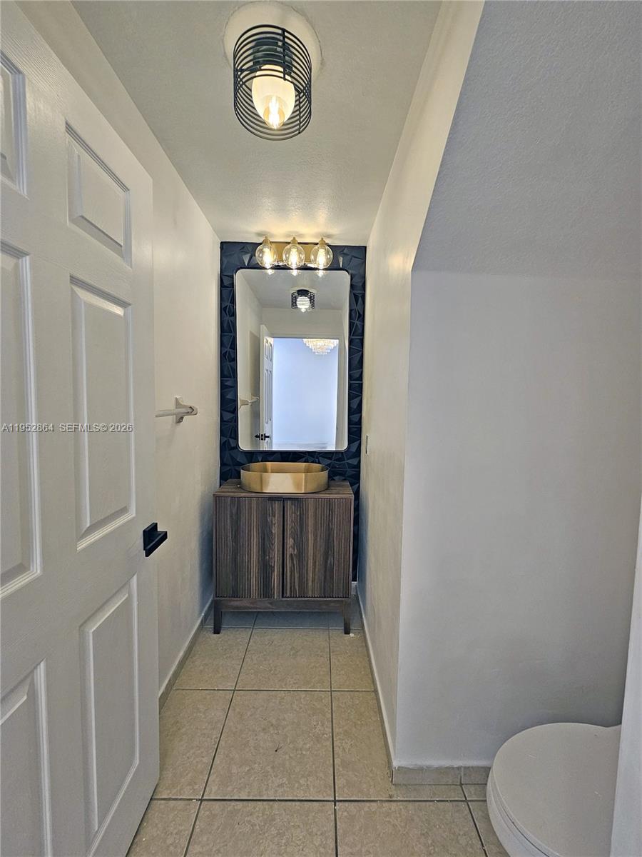A small bathroom features a wood vanity, a gold vessel sink, and a textured wall — 8371 SW 124th Ave # 12, Miami FL 33183, MIAMI, FL
