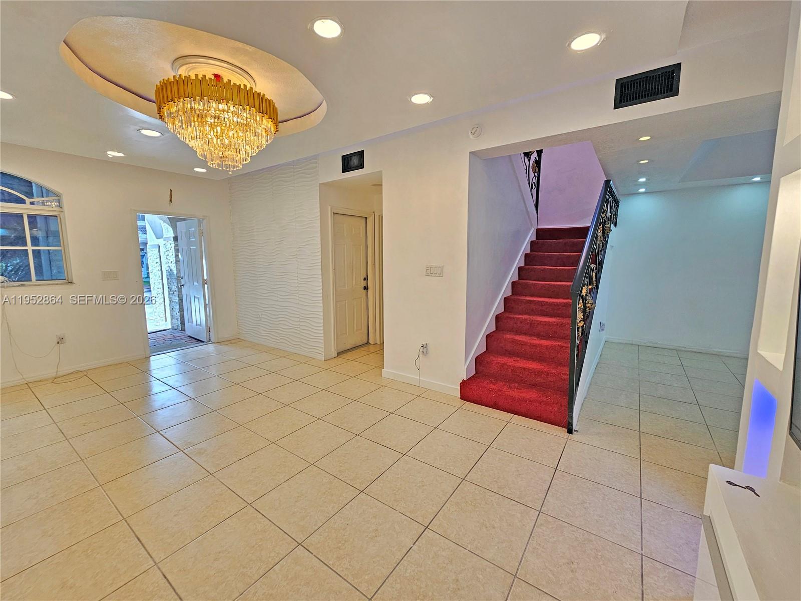 An entryway with tiled floors, a crystal chandelier, and a red-carpeted staircase — 8371 SW 124th Ave # 12, Miami FL 33183, MIAMI, FL