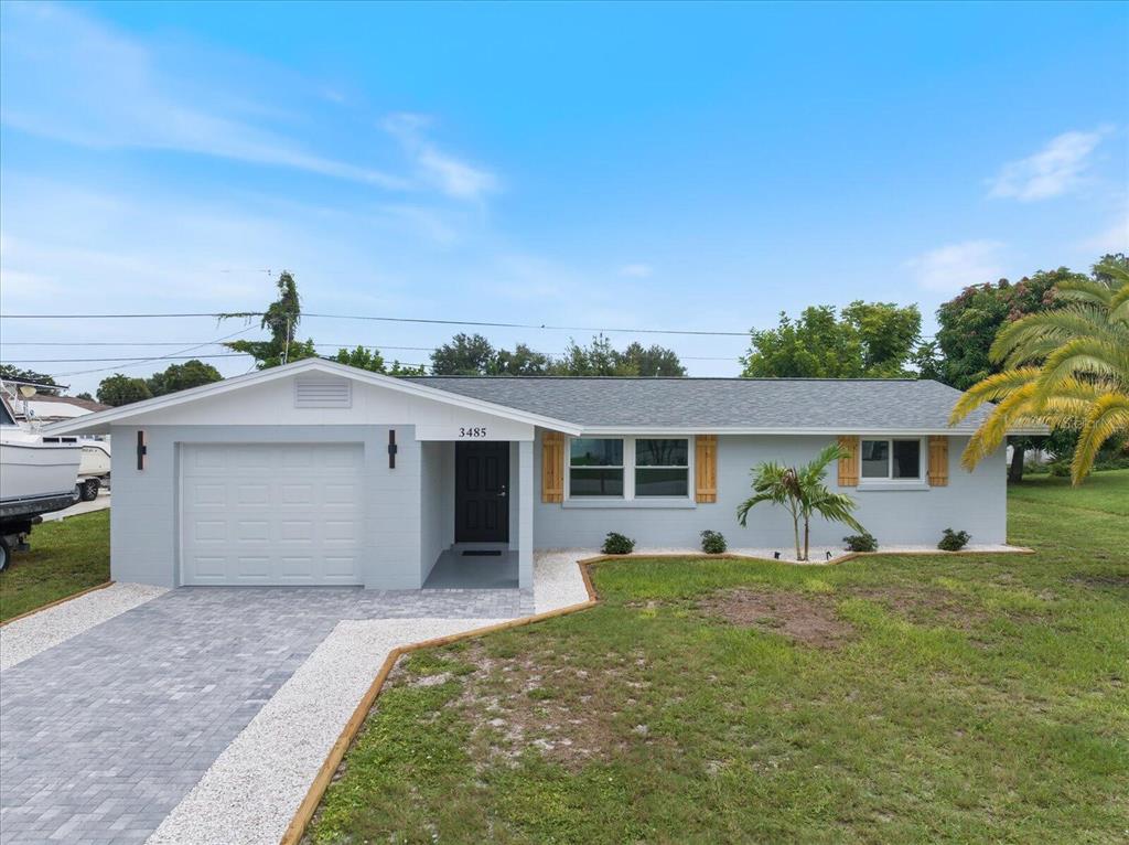 A single-story house with a gray exterior, a paved driveway, and a small front lawn — 3485 ROSLYN ROAD, VENICE, FL
