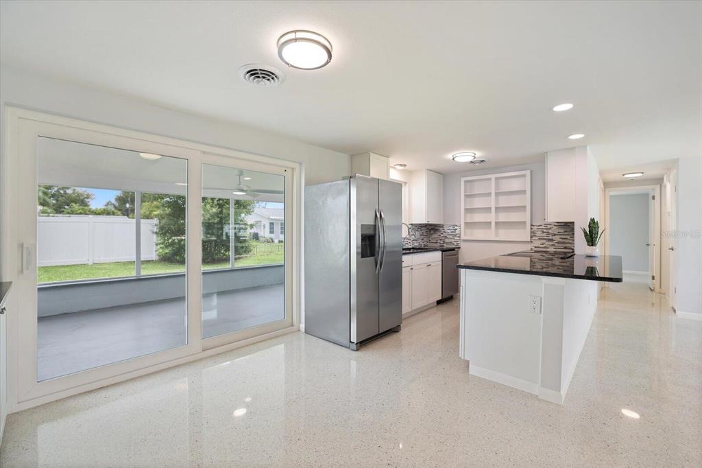 A kitchen with white cabinets, stainless steel appliances, and a sliding glass door to a patio — 3485 ROSLYN ROAD, VENICE, FL