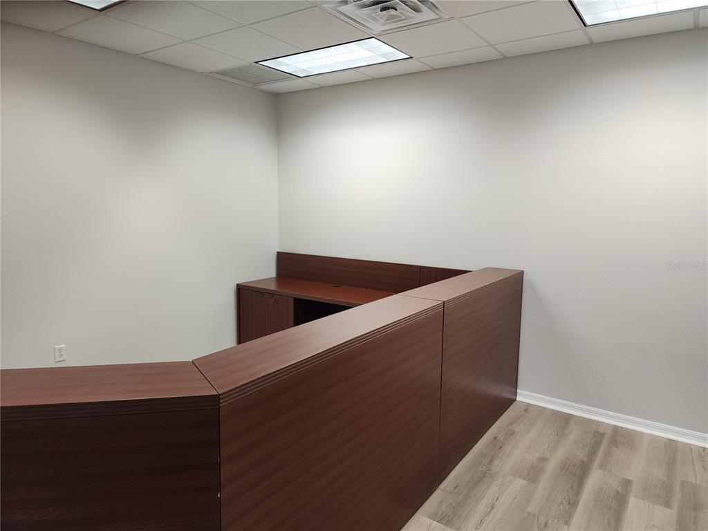 An office space features a dark wood reception desk, light grey walls, and wood-look flooring — 17801 MURDOCK CIRCLE UNIT C, PORT CHARLOTTE, FL