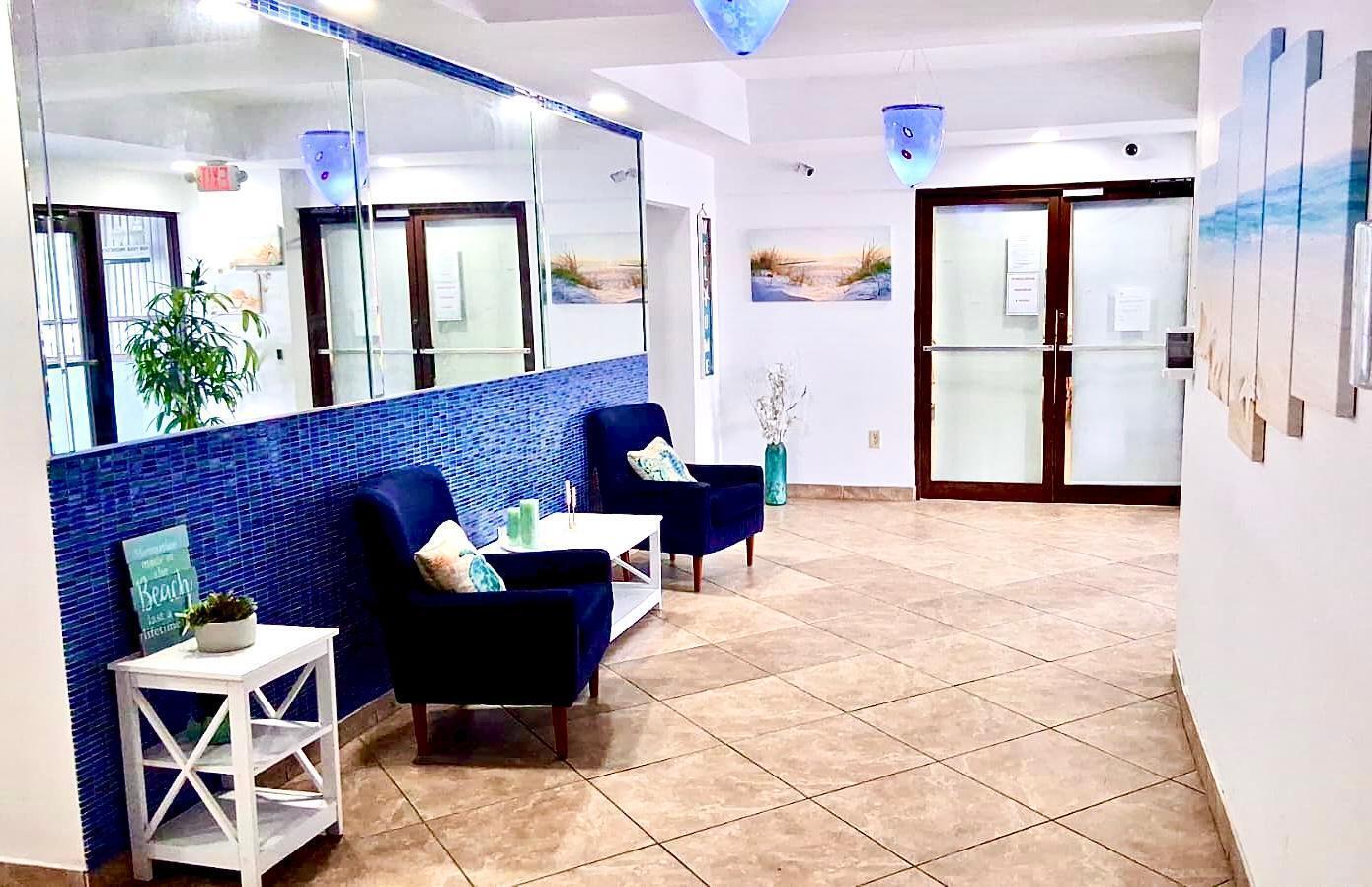 A lobby area features blue tiled walls, two dark armchairs, and a white side table — 7300 Wayne Avenue # 213, Miami Beach FL 33141, MIAMI BEACH, FL