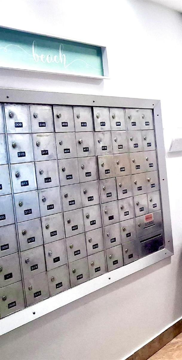 A wall-mounted metal mailbox unit with numbered compartments is positioned below a beach sign — 7300 Wayne Avenue # 213, Miami Beach FL 33141, MIAMI BEACH, FL