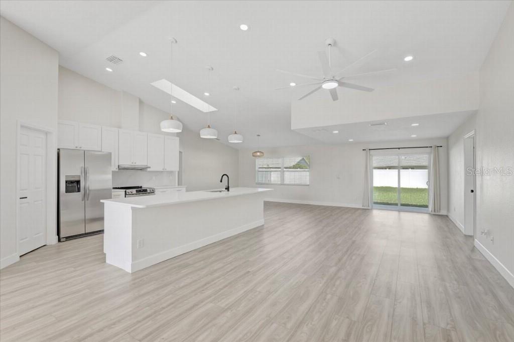 A bright, open-concept kitchen and living area with white cabinets, a large island, and flooring — 6501 68TH DRIVE E, PALMETTO, FL