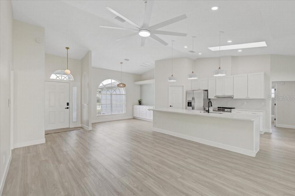 A bright, open-concept kitchen and living area features white cabinetry, a large island, and flooring — 6501 68TH DRIVE E, PALMETTO, FL