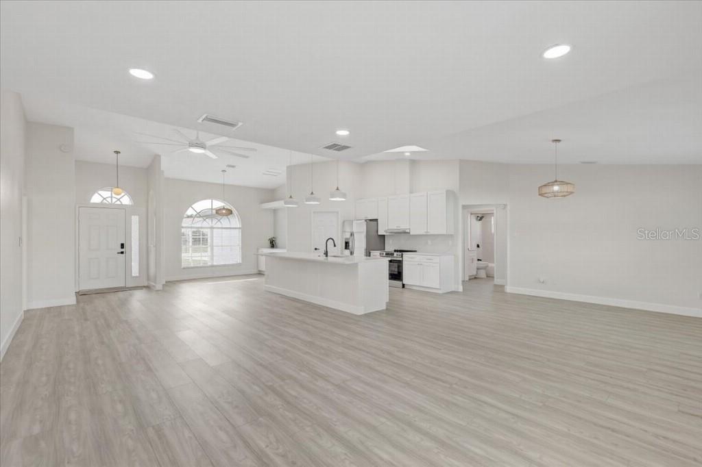 An open-concept kitchen and living area features white cabinetry, a central island, and light flooring — 6501 68TH DRIVE E, PALMETTO, FL