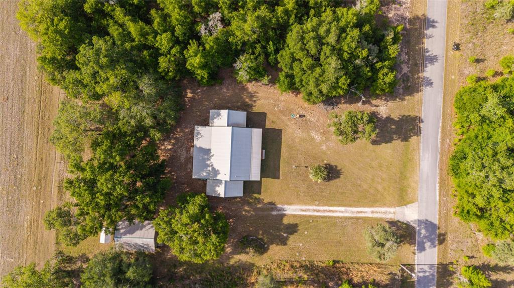 An aerial view shows a house with a metal roof surrounded by trees and grass — 1230 SW VALENCIA HEIGHTS AVENUE, DUNNELLON, FL