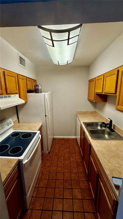 A galley kitchen features wood cabinets, laminate countertops, a white stove, and a white refrigerator — 6519 W NEWBERRY ROAD UNIT 812, GAINESVILLE, FL