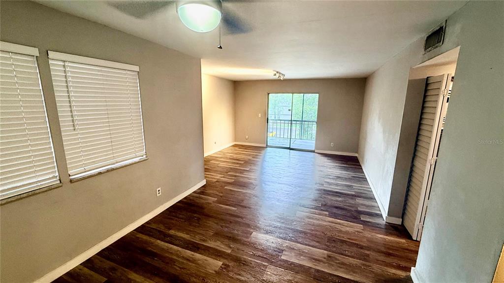 An empty living room features wood-look flooring, gray walls, a ceiling fan, and sliding glass doors — 6519 W NEWBERRY ROAD UNIT 812, GAINESVILLE, FL