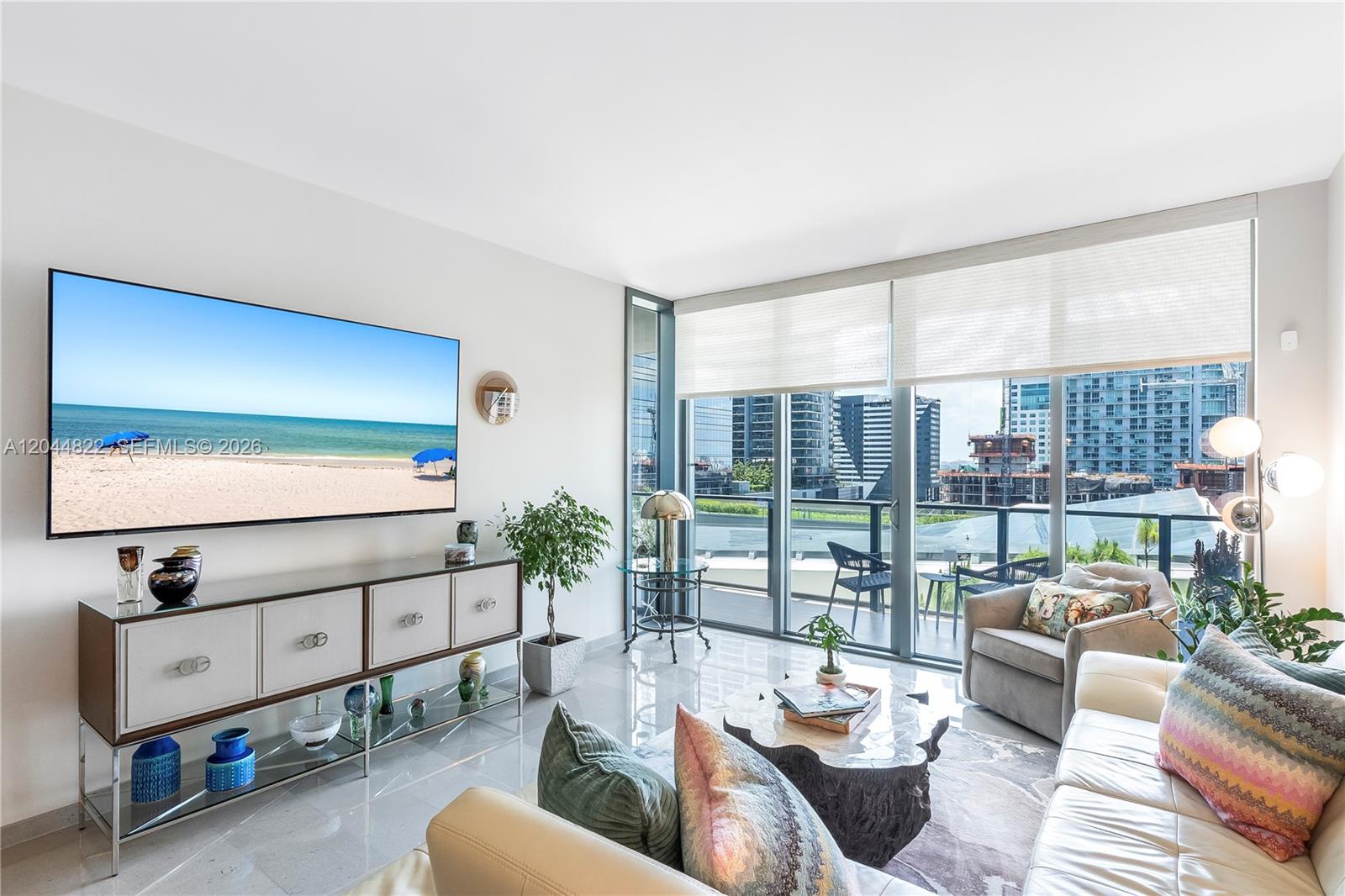 A modern living room features a large wall-mounted television, white cabinetry, and floor-to-ceiling windows — 68 SE 6th St # 810, Miami FL 33131, MIAMI, FL