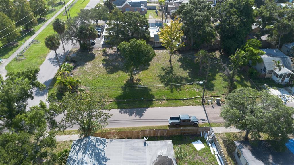 An aerial view shows a vacant, grassy residential lot with several trees and a parked truck — 5020 TANGERINE AVENUE S, GULFPORT, FL