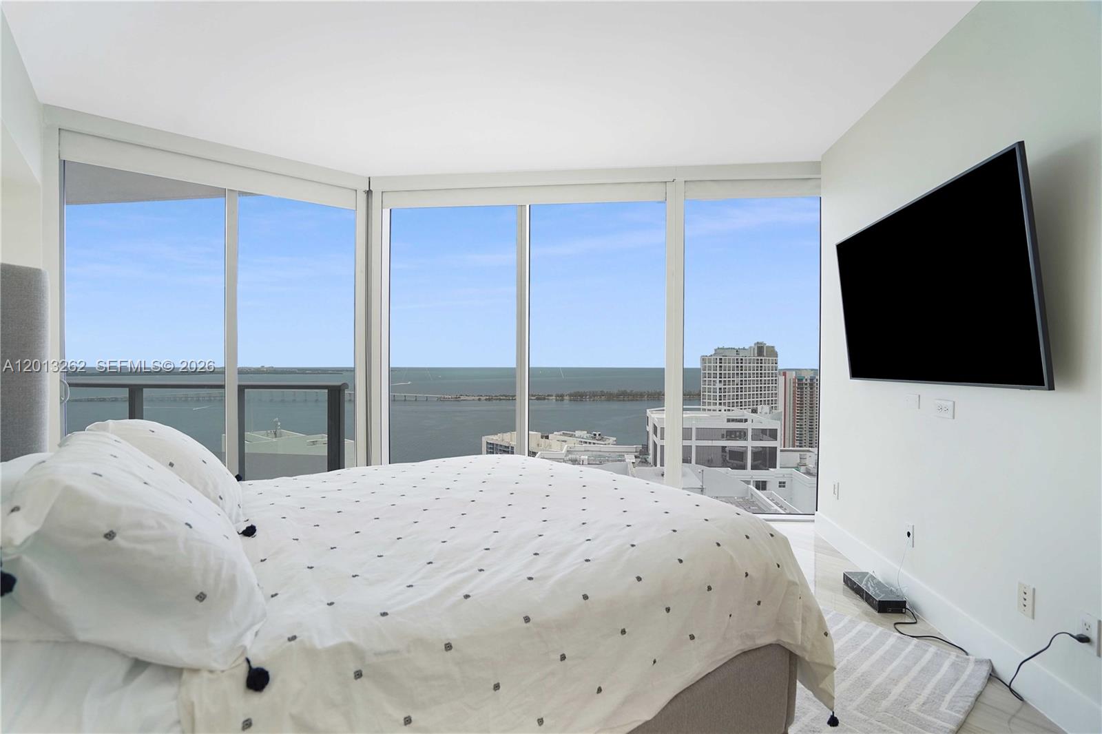 A bedroom features a bed, a wall-mounted television, and floor-to-ceiling windows overlooking the ocean — 1300 Brickell Bay Dr # 3402, Miami FL 33131, MIAMI, FL