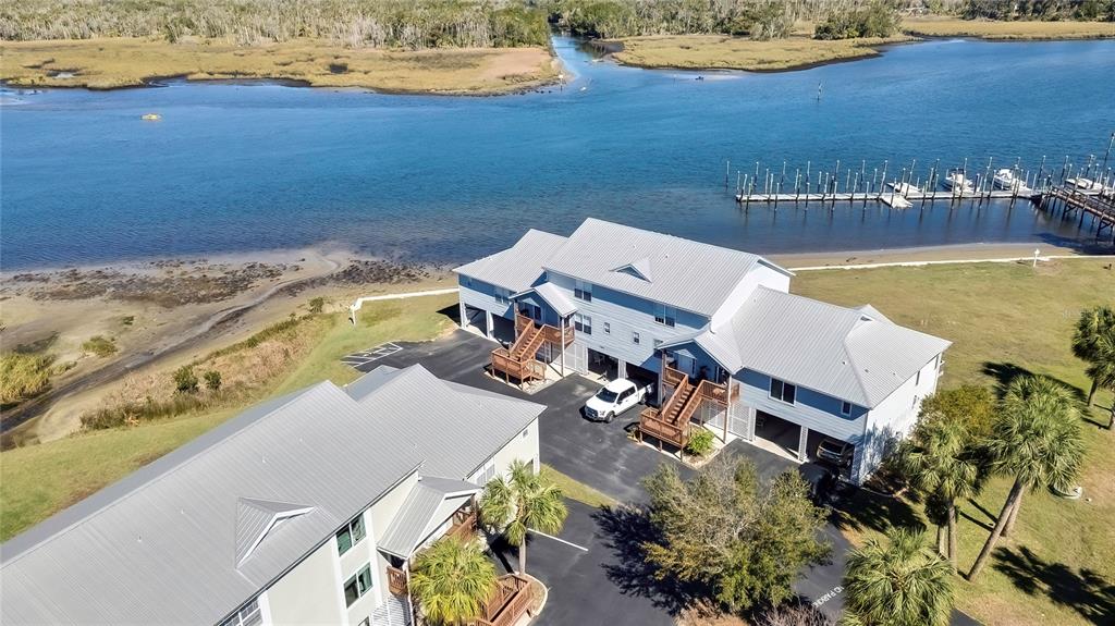 An aerial view shows two multi-story buildings with metal roofs near a coastal waterway — 2855 N RIVERS EDGE BOULEVARD UNIT 213, CRYSTAL RIVER, FL