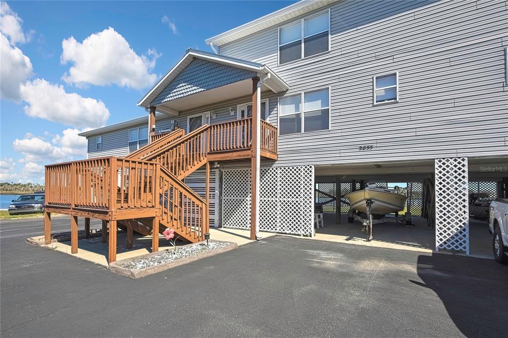 An elevated house with a wooden staircase, lattice skirting, and a boat parked underneath — 2855 N RIVERS EDGE BOULEVARD UNIT 213, CRYSTAL RIVER, FL