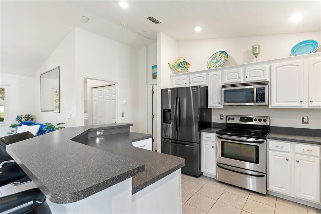 A kitchen features white cabinets, stainless steel appliances, and a dark gray countertop island — 6225 AMARYLLIS DRIVE, INDIAN LAKE ESTATES, FL