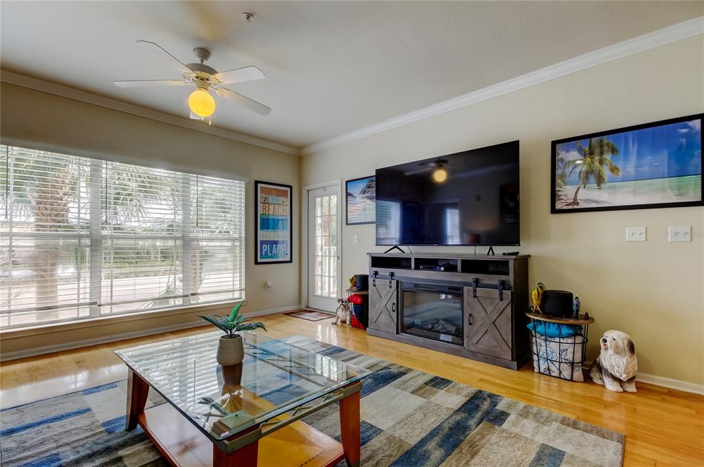 A living room features a glass coffee table, a television on a media console, and blinds — 1216 S MISSOURI AVENUE UNIT 220, CLEARWATER, FL