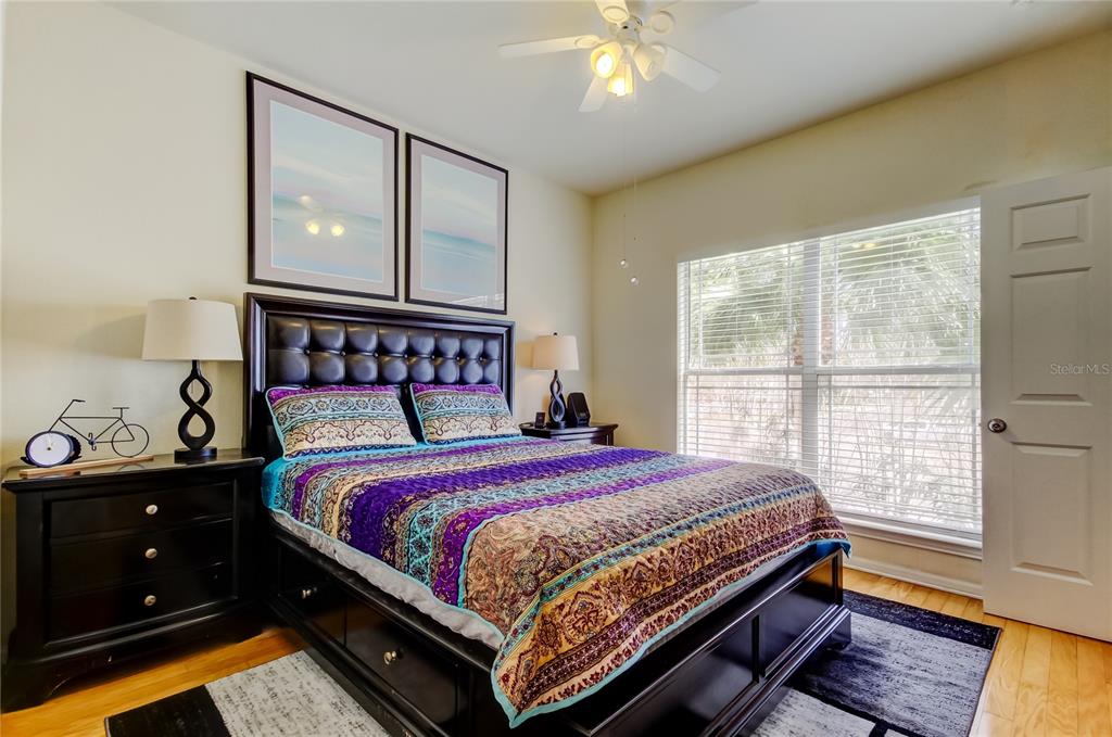 A bedroom features a tufted headboard, a patterned quilt, two nightstands, and a ceiling fan — 1216 S MISSOURI AVENUE UNIT 220, CLEARWATER, FL