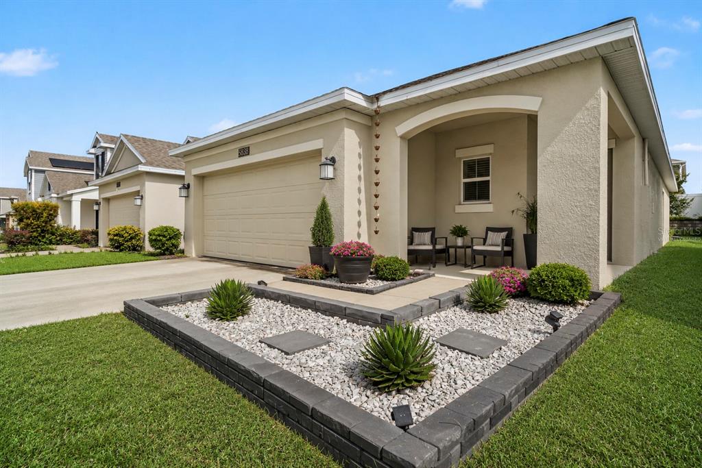 A single-story house exterior features a garage, a covered porch, and a landscaped rock garden — 6838 WILSON HAMMOCK AVENUE, GROVELAND, FL