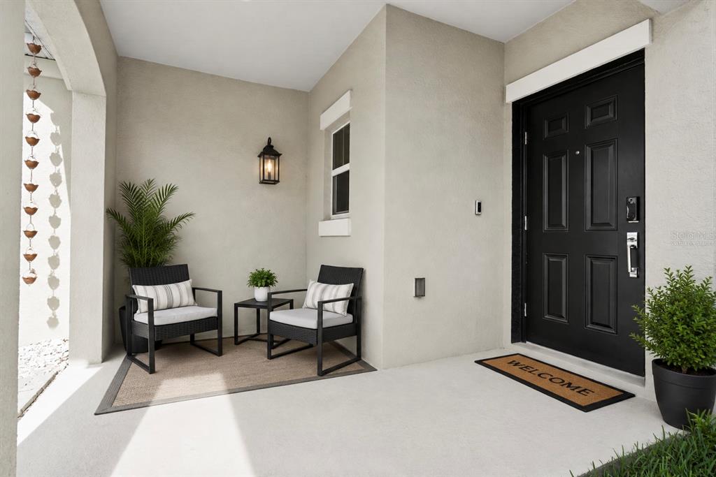 A covered front porch features two black chairs, a small table, and a black door — 6838 WILSON HAMMOCK AVENUE, GROVELAND, FL