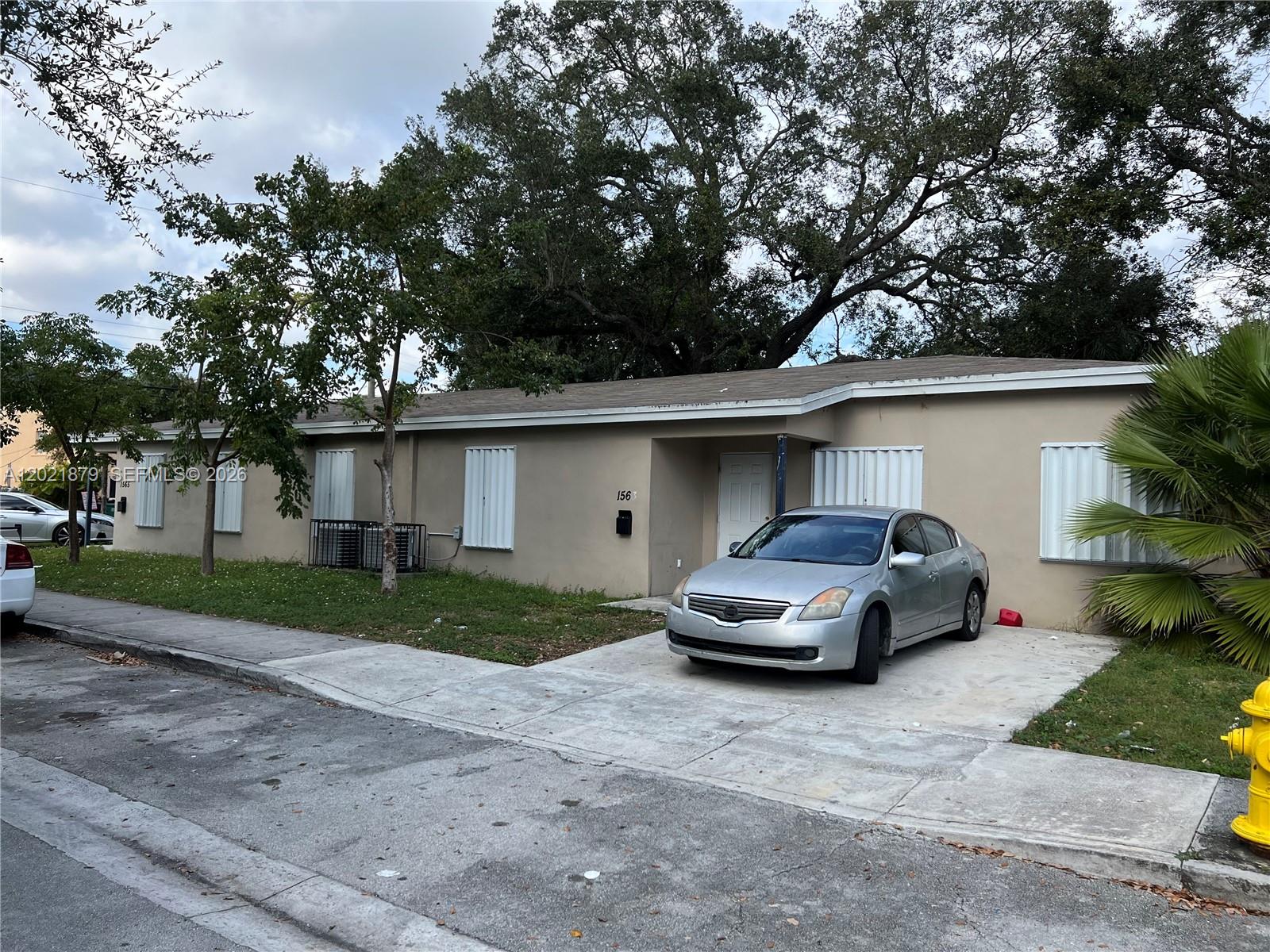 A single-story tan house with a silver sedan parked in the concrete driveway — 1565 NW 47th St, Miami FL 33142, MIAMI, FL