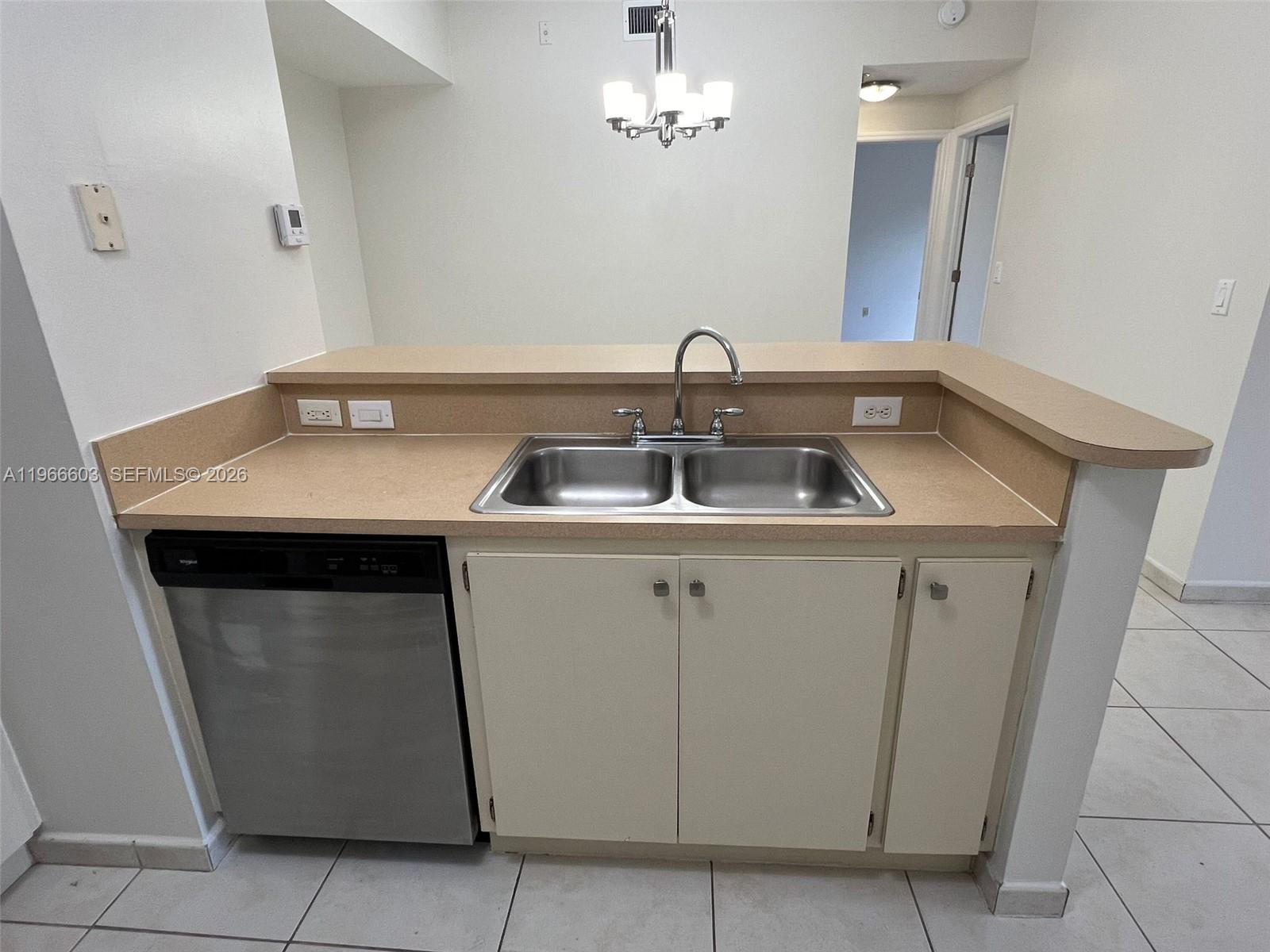A kitchen sink area features a stainless steel dishwasher, beige countertops, and white cabinets — 7220 NW 114th Ave # 307, Doral FL 33178, DORAL, FL