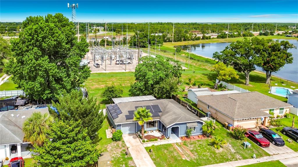 An aerial view shows a blue house with solar panels next to a power substation — 937 FLORIDA PARKWAY, KISSIMMEE, FL
