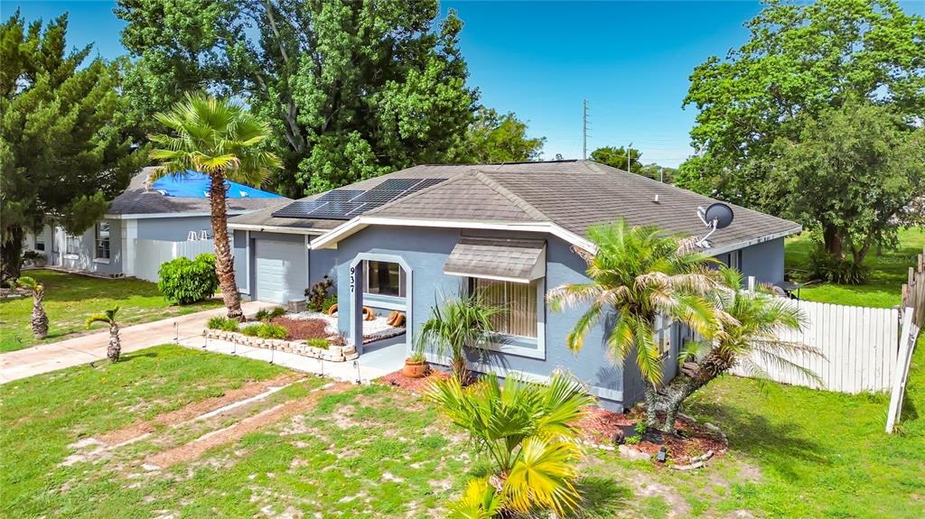 A blue single-story house with a gray roof, solar panels, and palm trees in the yard — 937 FLORIDA PARKWAY, KISSIMMEE, FL