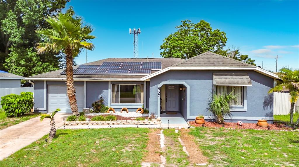 A single-story house with a gray exterior, solar panels, and a palm tree in front — 937 FLORIDA PARKWAY, KISSIMMEE, FL