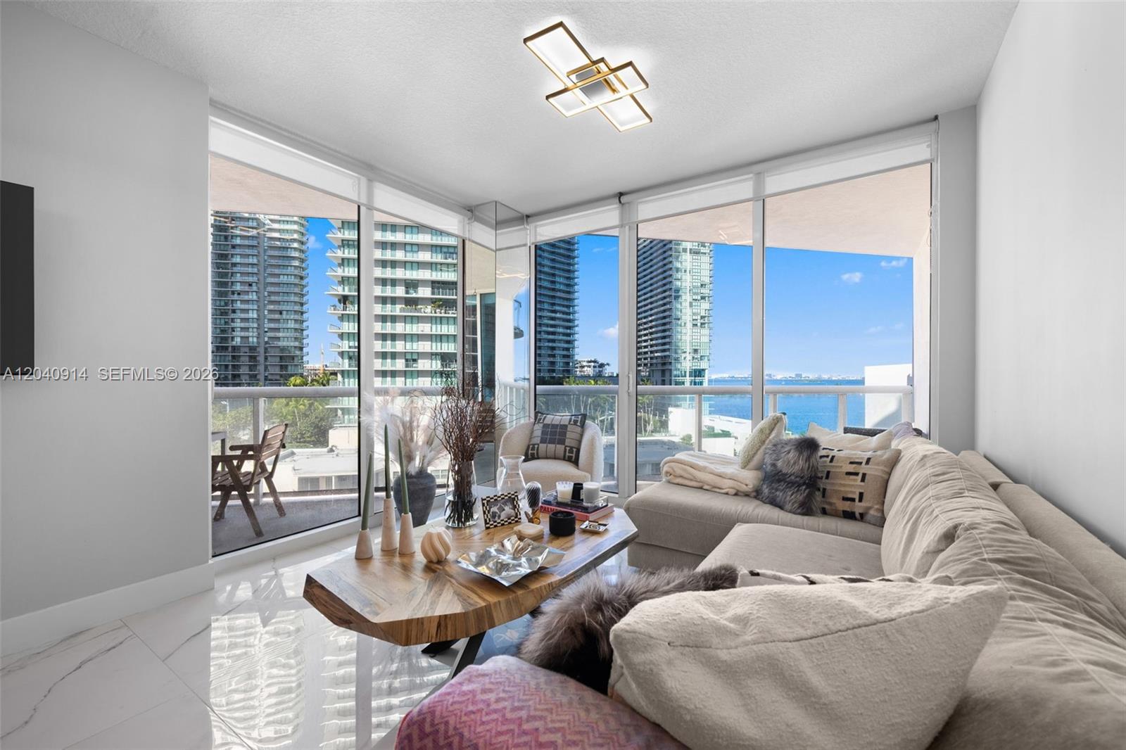 A living room features a sectional sofa, a wood coffee table, and floor-to-ceiling windows — 480 NE 30th St # 904, Miami FL 33137, MIAMI, FL