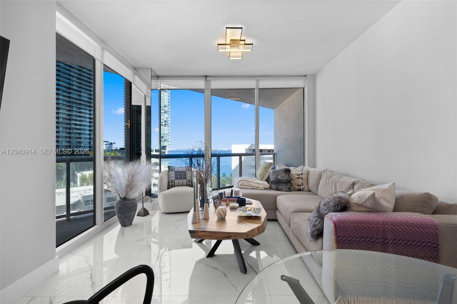 A modern living room features white marble floors, a sectional sofa, and floor-to-ceiling windows — 480 NE 30th St # 904, Miami FL 33137, MIAMI, FL