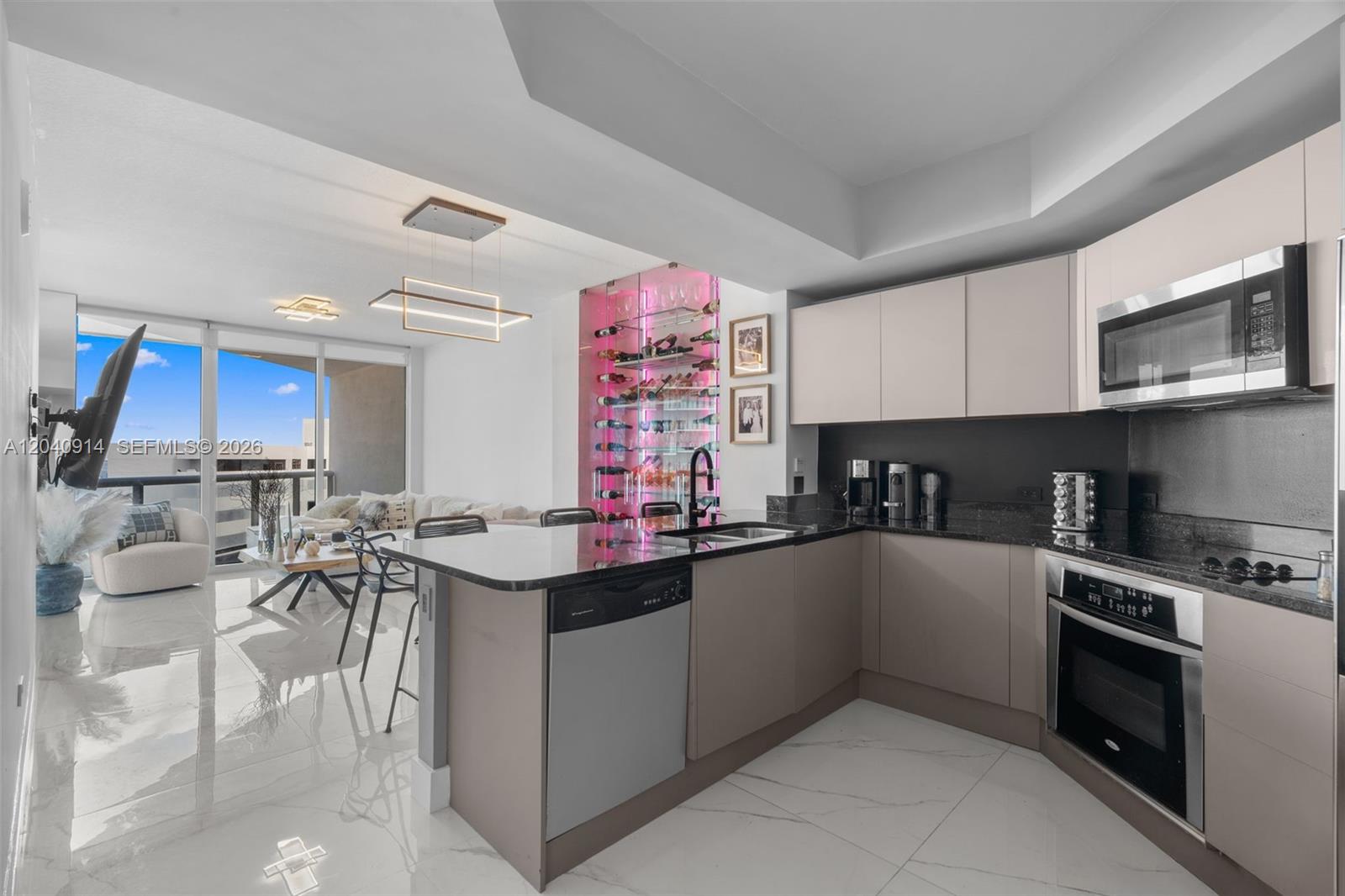 A modern kitchen features light-toned cabinets, dark granite countertops, and a backlit glass wine display — 480 NE 30th St # 904, Miami FL 33137, MIAMI, FL