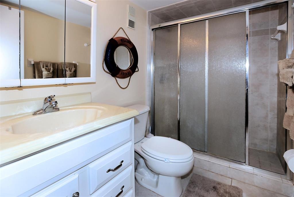 A bathroom features a white vanity, a toilet, and a glass-enclosed walk-in shower — 1571 S ATLANTIC AVENUE UNIT 103, NEW SMYRNA BEACH, FL