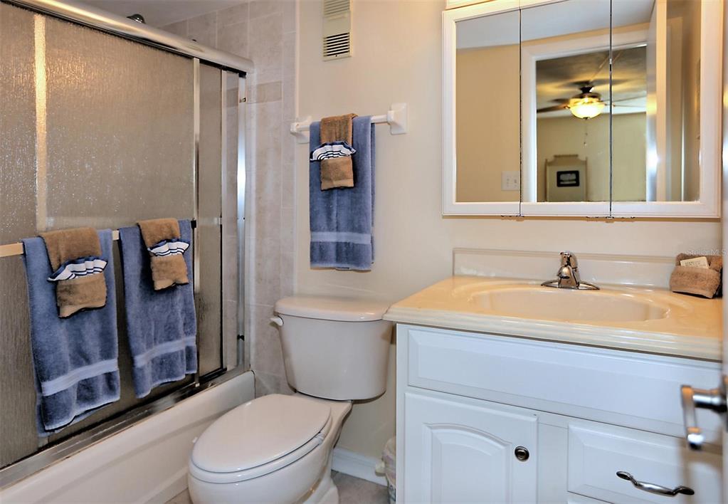 A bathroom features a white vanity, a toilet, and a shower with sliding glass doors — 1571 S ATLANTIC AVENUE UNIT 103, NEW SMYRNA BEACH, FL