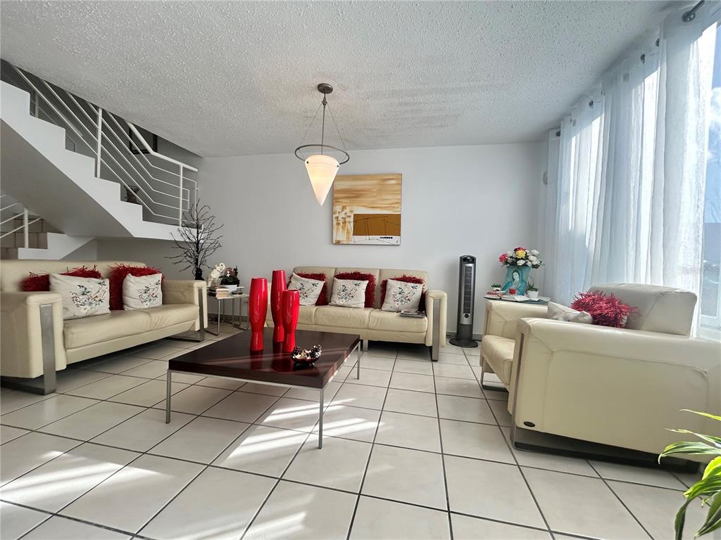 A living room features white tile floors, cream leather sofas, and a staircase with railings — PG-124 VIA ARCOIRIS, TRUJILLO ALTO, PR