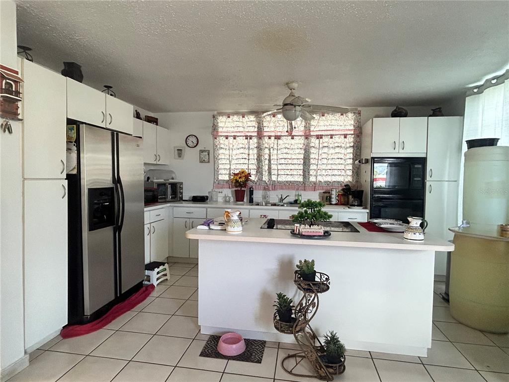 A kitchen features white cabinetry, stainless steel appliances, a center island, and tiled flooring — PG-124 VIA ARCOIRIS, TRUJILLO ALTO, PR