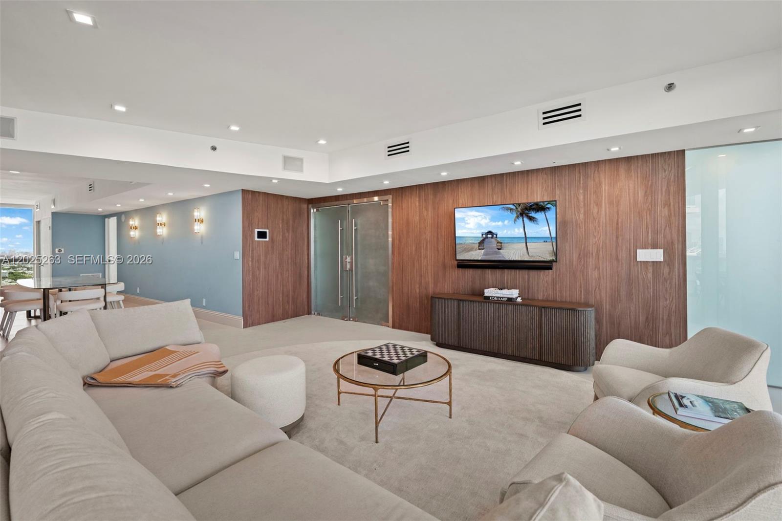 A living room features a wood-paneled accent wall, a television, and neutral-toned furniture — 1000 S Pointe Dr # 2803, Miami Beach FL 33139, MIAMI BEACH, FL