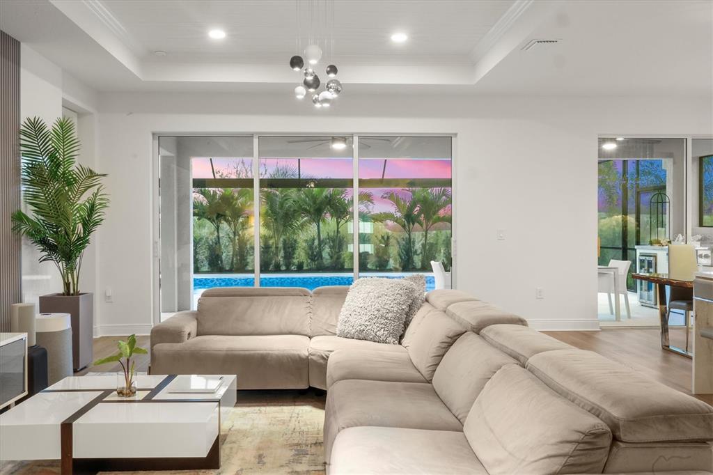 A living room with a beige sectional sofa, a white coffee table, and sliding glass doors — 17727 SAVORY MIST CIRCLE, BRADENTON, FL