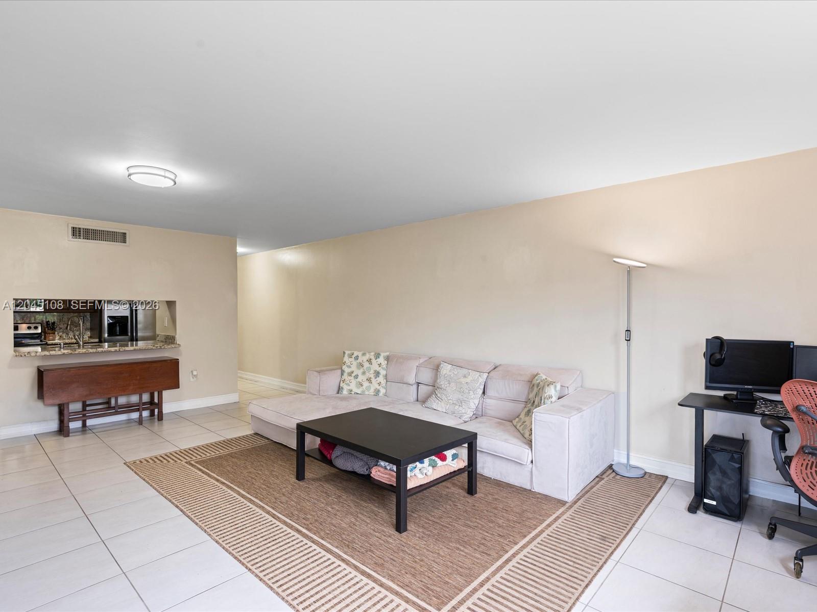 A living room features a light-colored sectional sofa, a coffee table, and a small desk — 571 NW 107th Ave # 107, Miami FL 33172, MIAMI, FL