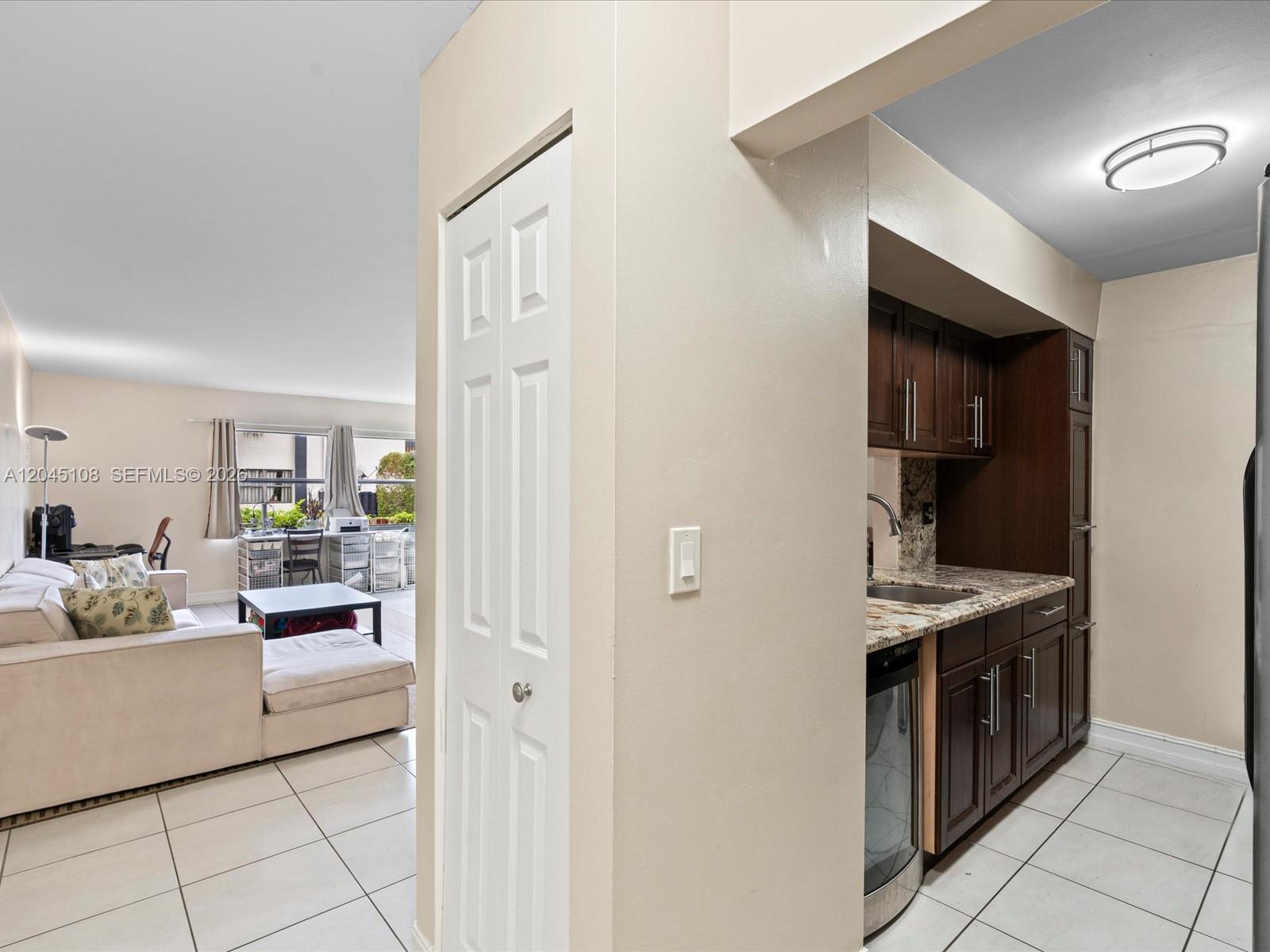 A view from a tiled kitchen area looking into a living room with a sofa — 571 NW 107th Ave # 107, Miami FL 33172, MIAMI, FL