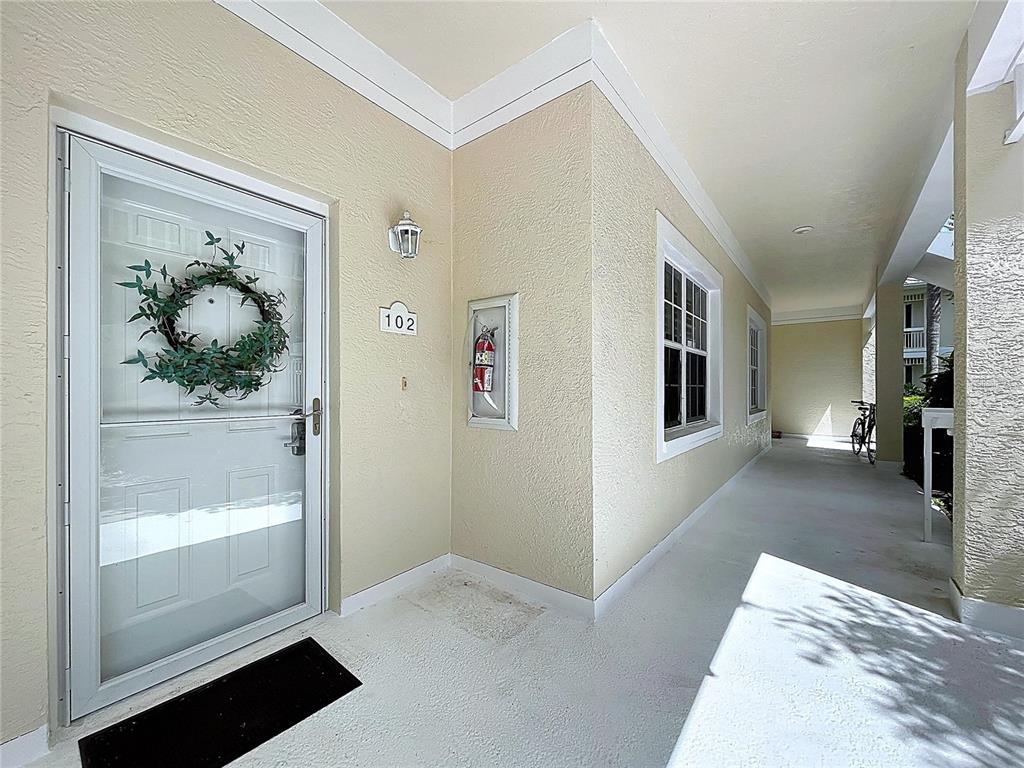 A covered exterior walkway leads to the front entrance of a unit numbered 102 — 3803 54TH DRIVE W UNIT 102, BRADENTON, FL
