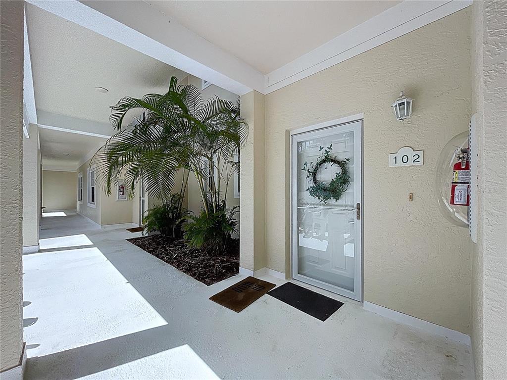 An exterior view shows a covered walkway leading to a front door numbered 102 — 3803 54TH DRIVE W UNIT 102, BRADENTON, FL